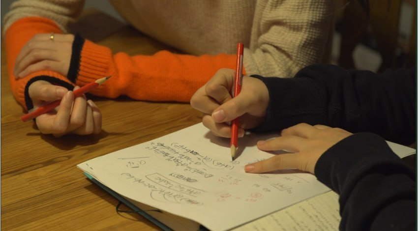 학생의 노트 필기를 옆에서 살펴보는 학습 지도 장면